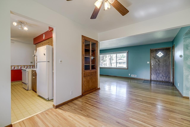 unfurnished living room with ceiling fan, light wood finished floors, and baseboards