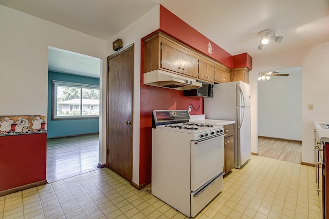 kitchen featuring white appliances, under cabinet range hood, a ceiling fan, light countertops, and light tile patterned floors