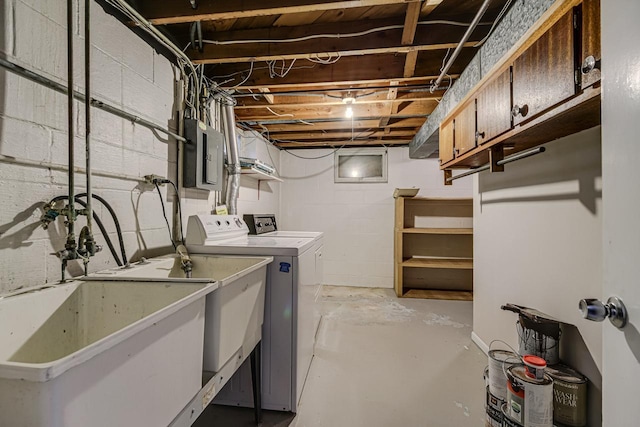 unfinished basement featuring separate washer and dryer, a sink, electric panel, and concrete block wall