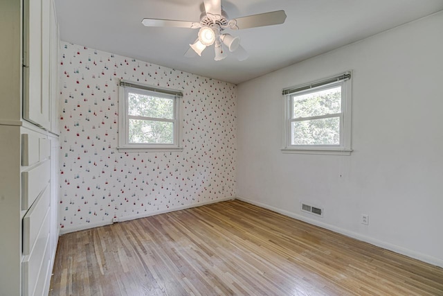 unfurnished room featuring plenty of natural light, baseboards, light wood finished floors, and a ceiling fan