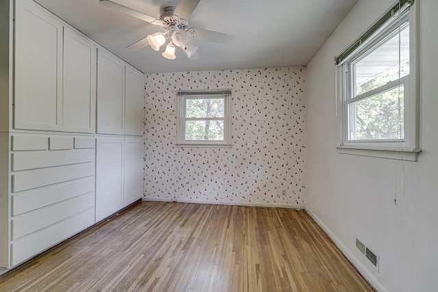 unfurnished room with baseboards, light wood finished floors, ceiling fan, and wallpapered walls