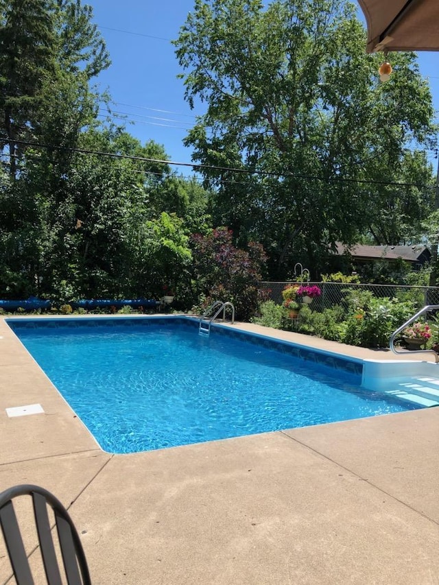 view of swimming pool featuring fence and a patio