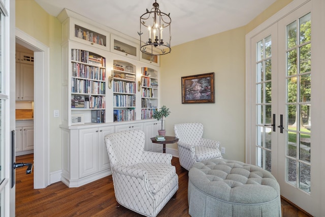living area featuring a chandelier, dark wood-style flooring, baseboards, and french doors