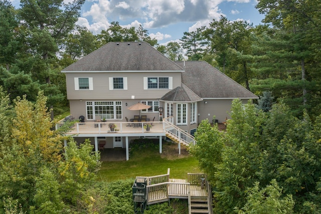 back of house featuring a wooden deck, stairs, roof with shingles, and a lawn