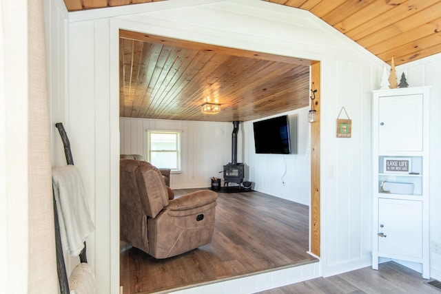 living area featuring a wood stove, wooden ceiling, wood finished floors, and lofted ceiling