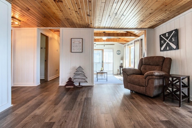 sitting room with wood walls, wood ceiling, dark wood finished floors, stairs, and baseboards