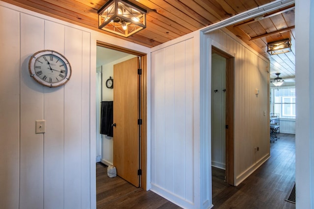 hall featuring wooden ceiling, dark wood-type flooring, baseboards, and a chandelier