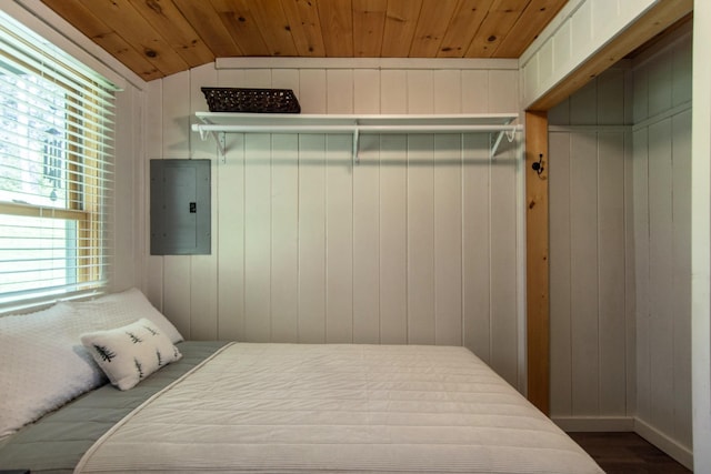 bedroom with electric panel, vaulted ceiling, wood finished floors, wooden ceiling, and wood walls