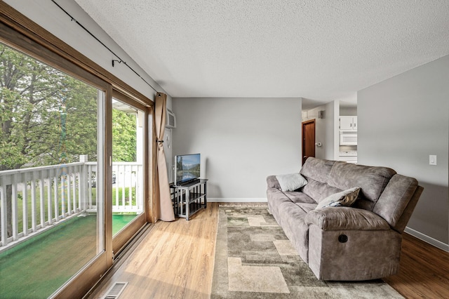 2478 Cobble Hill Alcove Unit C, Woodbury, MN 55125 - living room featuring light wood finished floors, a textured ceiling, baseboards, and a wall mounted AC