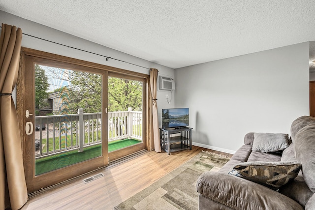 2478 Cobble Hill Alcove Unit C, Woodbury, MN 55125 - living room featuring wood finished floors, a textured ceiling, an AC wall unit, and baseboards