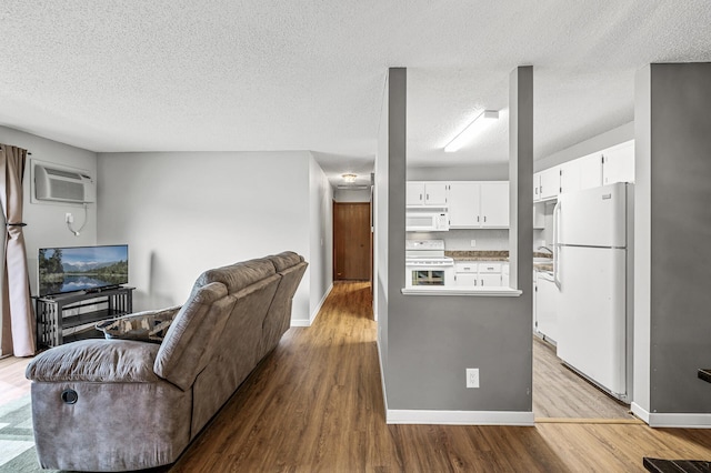 2478 Cobble Hill Alcove Unit C, Woodbury, MN 55125 - living area featuring a wall mounted air conditioner, wood finished floors, a textured ceiling, and baseboards
