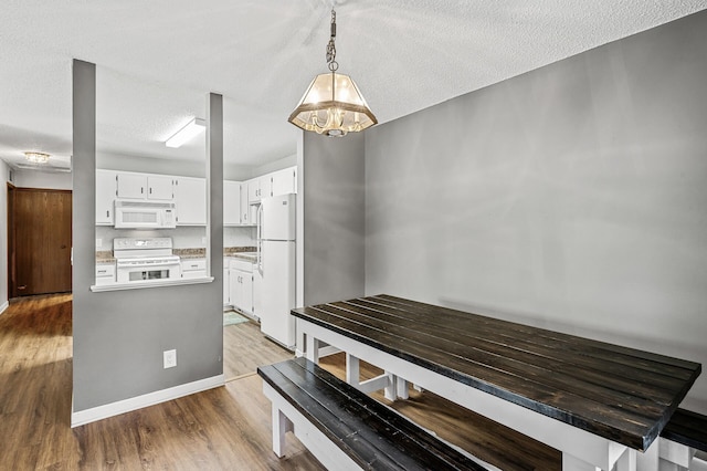 2478 Cobble Hill Alcove Unit C, Woodbury, MN 55125 - dining area with wood finished floors, a textured ceiling, a chandelier, and baseboards