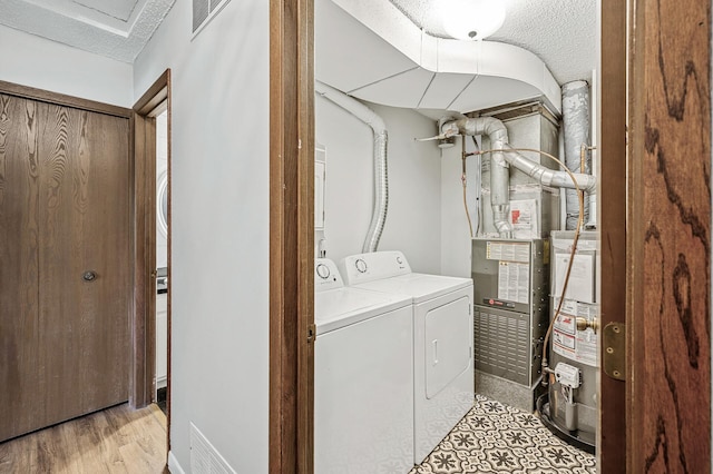 2478 Cobble Hill Alcove Unit C, Woodbury, MN 55125 - washroom with washer and clothes dryer, gas water heater, a textured ceiling, light wood finished floors, and heating unit
