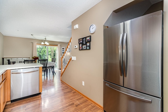 10916 181st Ln NW, Elk River, MN 55330 - kitchen with stainless steel appliances, light wood-type flooring, light countertops, a chandelier, and brown cabinets
