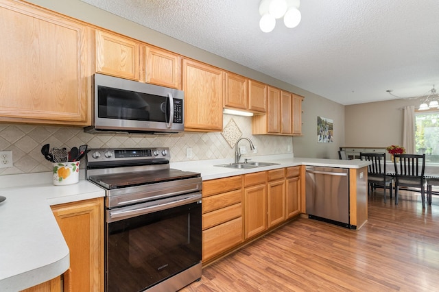 10916 181st Ln NW, Elk River, MN 55330 - kitchen featuring appliances with stainless steel finishes, a sink, light wood-type flooring, light countertops, and a textured ceiling