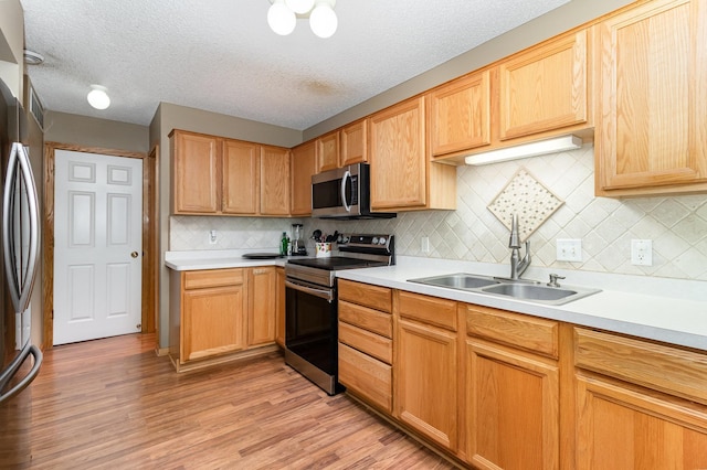 10916 181st Ln NW, Elk River, MN 55330 - kitchen with appliances with stainless steel finishes, a sink, light countertops, light wood-style flooring, and a textured ceiling