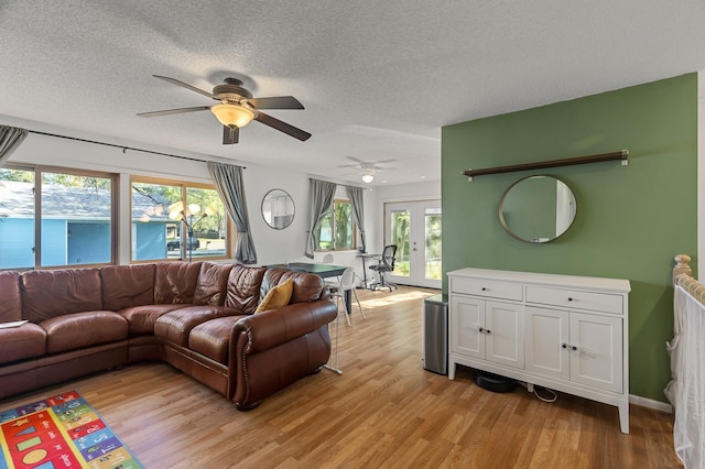 living room with light wood-style floors, ceiling fan, and a textured ceiling