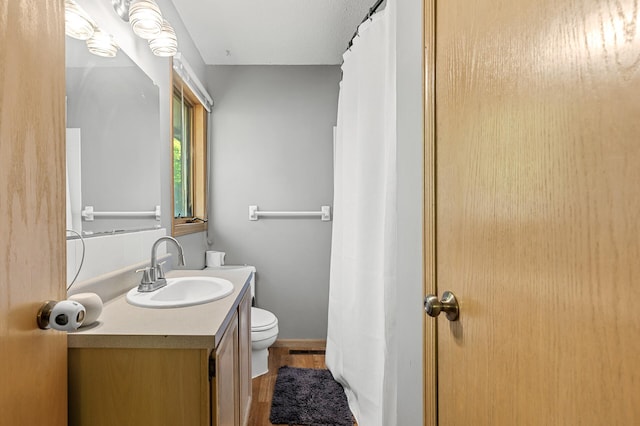 bathroom featuring wood finished floors, toilet, vanity, and baseboards