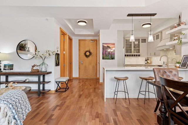 501 Main St N Unit 409, Stillwater, MN 55082 - kitchen featuring a kitchen breakfast bar, a raised ceiling, light countertops, tasteful backsplash, and light wood-type flooring