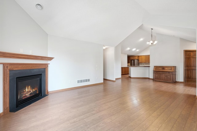 24107 Rivers Edge Rd, Rogers, MN 55374 - unfurnished living room featuring lofted ceiling, a fireplace with flush hearth, a chandelier, light wood-type flooring, and baseboards