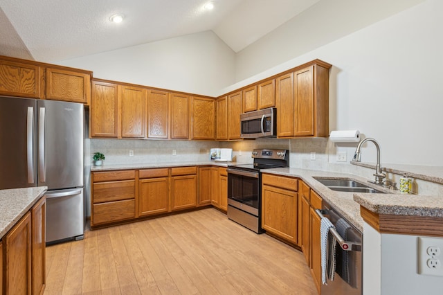 24107 Rivers Edge Rd, Rogers, MN 55374 - kitchen with appliances with stainless steel finishes, a sink, brown cabinetry, light wood-style flooring, and high vaulted ceiling