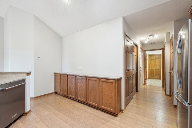 24107 Rivers Edge Rd, Rogers, MN 55374 - kitchen featuring appliances with stainless steel finishes, brown cabinets, light wood-style floors, a textured ceiling, and baseboards