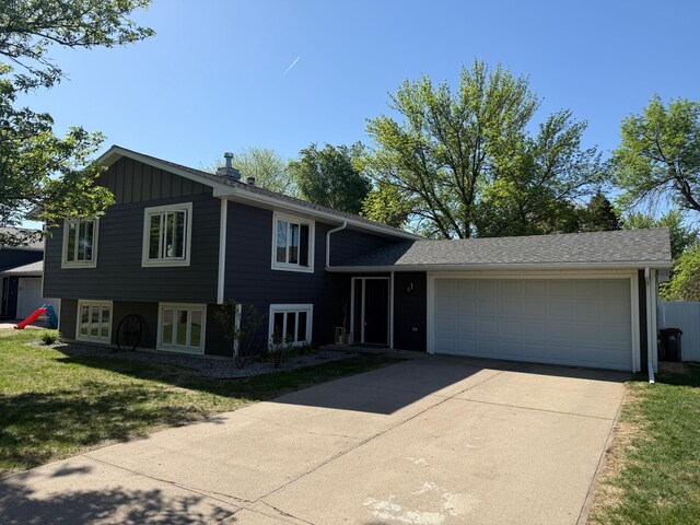 504 Fallwood Rd, Redwood Falls, MN 56283 - tri-level home featuring driveway, an attached garage, french doors, a front lawn, and board and batten siding