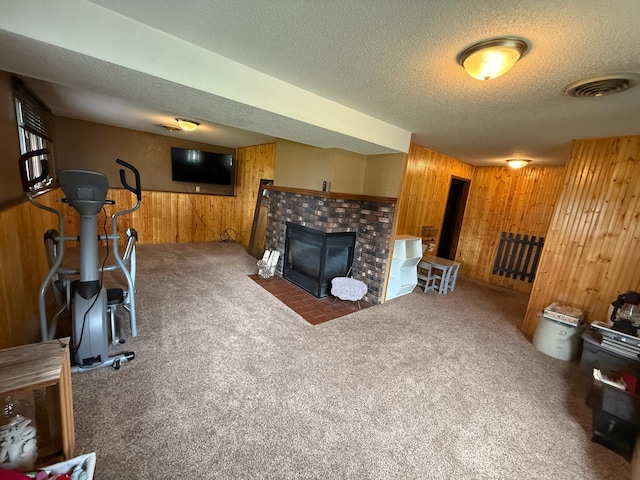 504 Fallwood Rd, Redwood Falls, MN 56283 - carpeted living room featuring wood walls, a textured ceiling, a fireplace with flush hearth, and a wainscoted wall