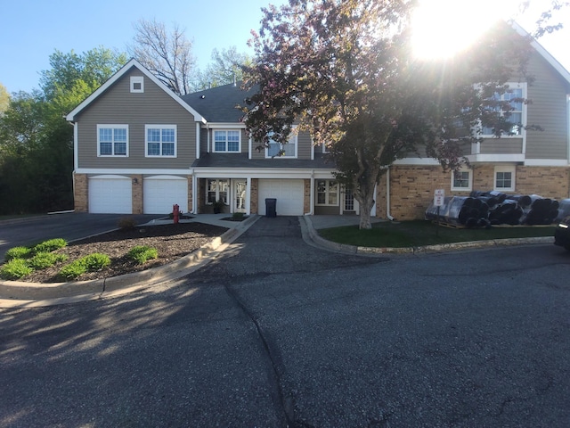 townhome / multi-family property featuring driveway, a garage, and brick siding