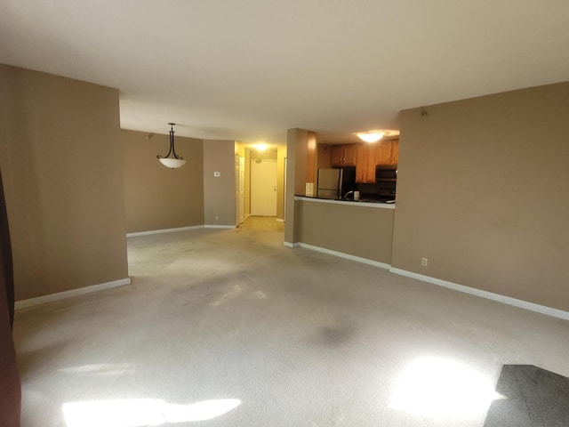 unfurnished living room featuring light carpet and baseboards