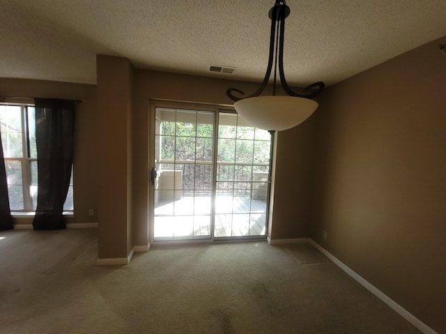 unfurnished dining area featuring carpet, a textured ceiling, and baseboards