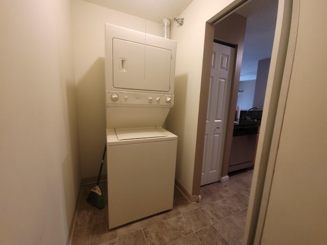 washroom with stacked washer / drying machine, baseboards, and tile patterned floors