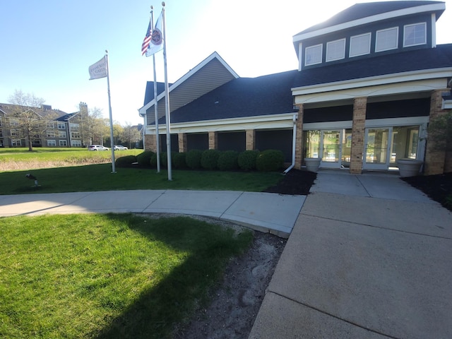 view of front of property featuring brick siding, a front yard, and roof with shingles