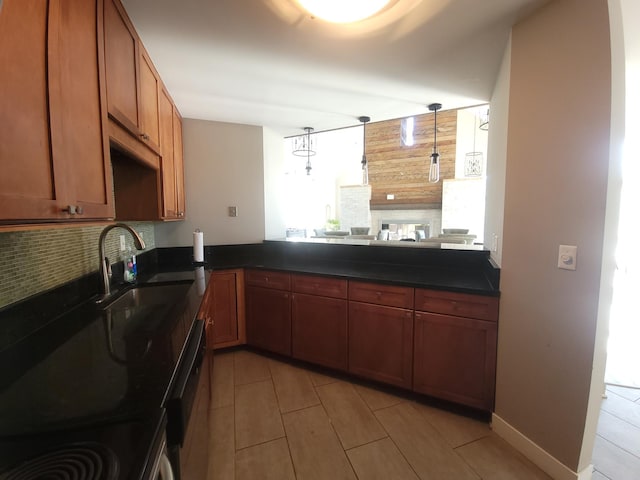 kitchen with tasteful backsplash, dark countertops, light tile patterned flooring, a sink, and brown cabinets