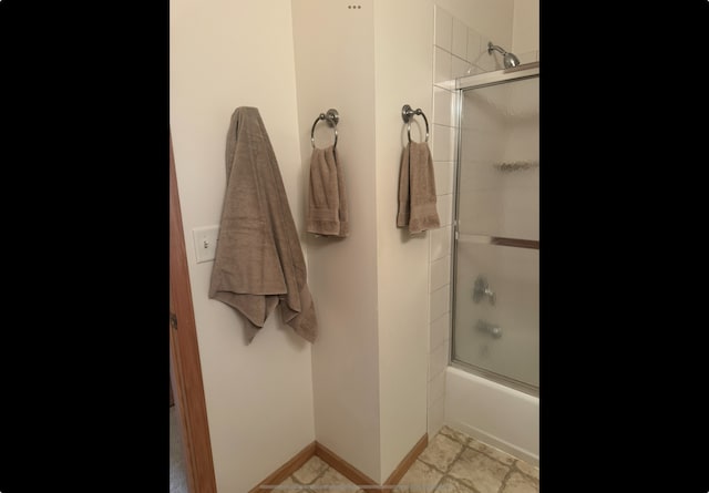 full bathroom featuring shower / bath combination with glass door and baseboards