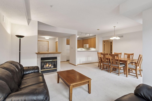 living room featuring light colored carpet, a tiled fireplace, and baseboards