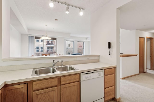 kitchen with white dishwasher, a sink, light colored carpet, light countertops, and decorative light fixtures