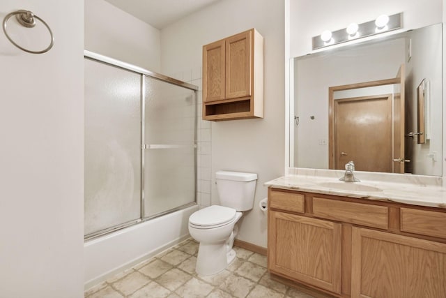 bathroom featuring toilet, vanity, shower / bath combination with glass door, and baseboards
