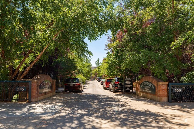 view of asphalt road featuring sidewalks and a gate