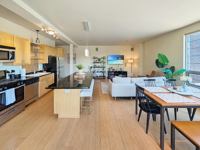 521 2nd St SE Unit 206, Minneapolis, MN 55414 - kitchen with appliances with stainless steel finishes, light brown cabinets, a breakfast bar, light wood-type flooring, and a kitchen island