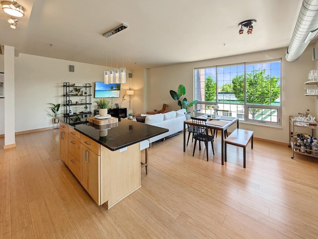 521 2nd St SE Unit 206, Minneapolis, MN 55414 - kitchen with dark countertops, light wood-style floors, light brown cabinetry, a breakfast bar, and a kitchen island