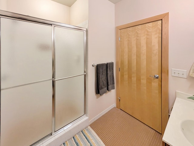521 2nd St SE Unit 206, Minneapolis, MN 55414 - bathroom featuring a stall shower, vanity, baseboards, and tile patterned flooring