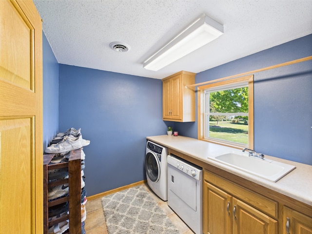 laundry area with washing machine and dryer, cabinet space, and a textured ceiling