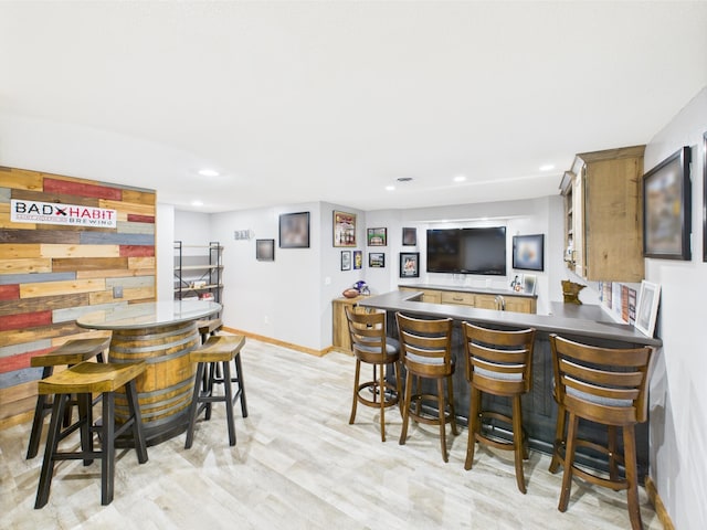 dining area with bar, light wood-style flooring, recessed lighting, and baseboards