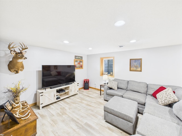 living area with baseboards, recessed lighting, and light wood-type flooring