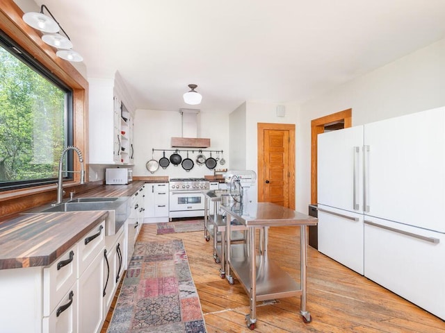 41218 Nelson Rd, North Branch, MN 55056 - kitchen featuring freestanding refrigerator, high end stove, a sink, stainless steel countertops, and white cabinetry