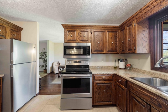 19800 See Gull Rd, Brainerd, MN 56401 - kitchen with stainless steel appliances, a sink, a textured ceiling, light countertops, and light tile patterned flooring