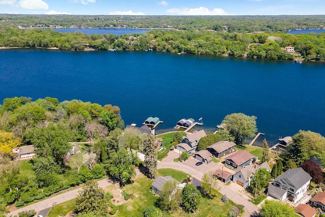 aerial perspective of suburban area featuring a nearby body of water and a heavily wooded area