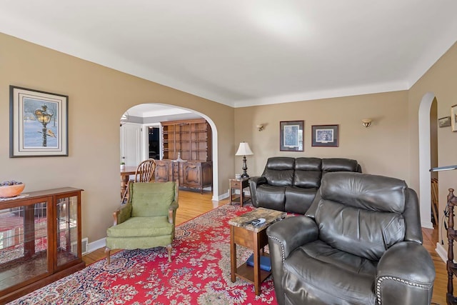 living room with arched walkways, light wood-style flooring, and baseboards