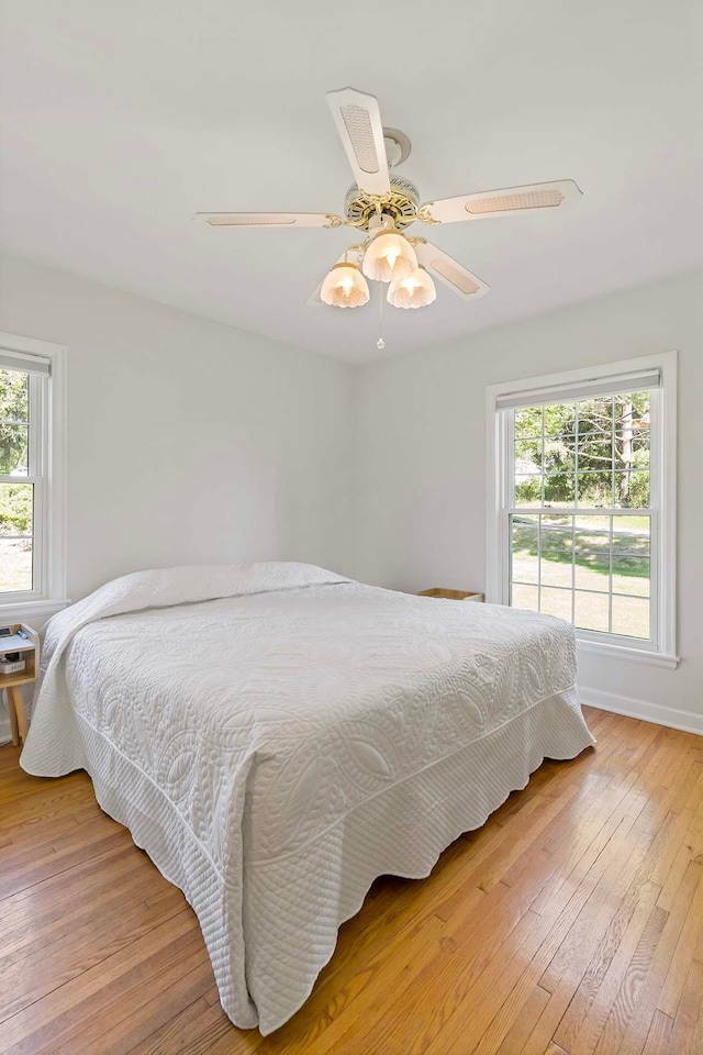 bedroom featuring light wood-style flooring, a ceiling fan, and baseboards